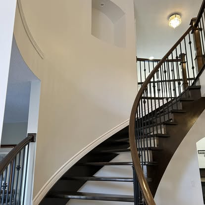 Curved staircase with dark wood finish and freshly painted white walls in Ottawa home