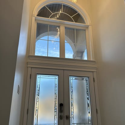 Custom front entrance with arched transom window and double doors painted white